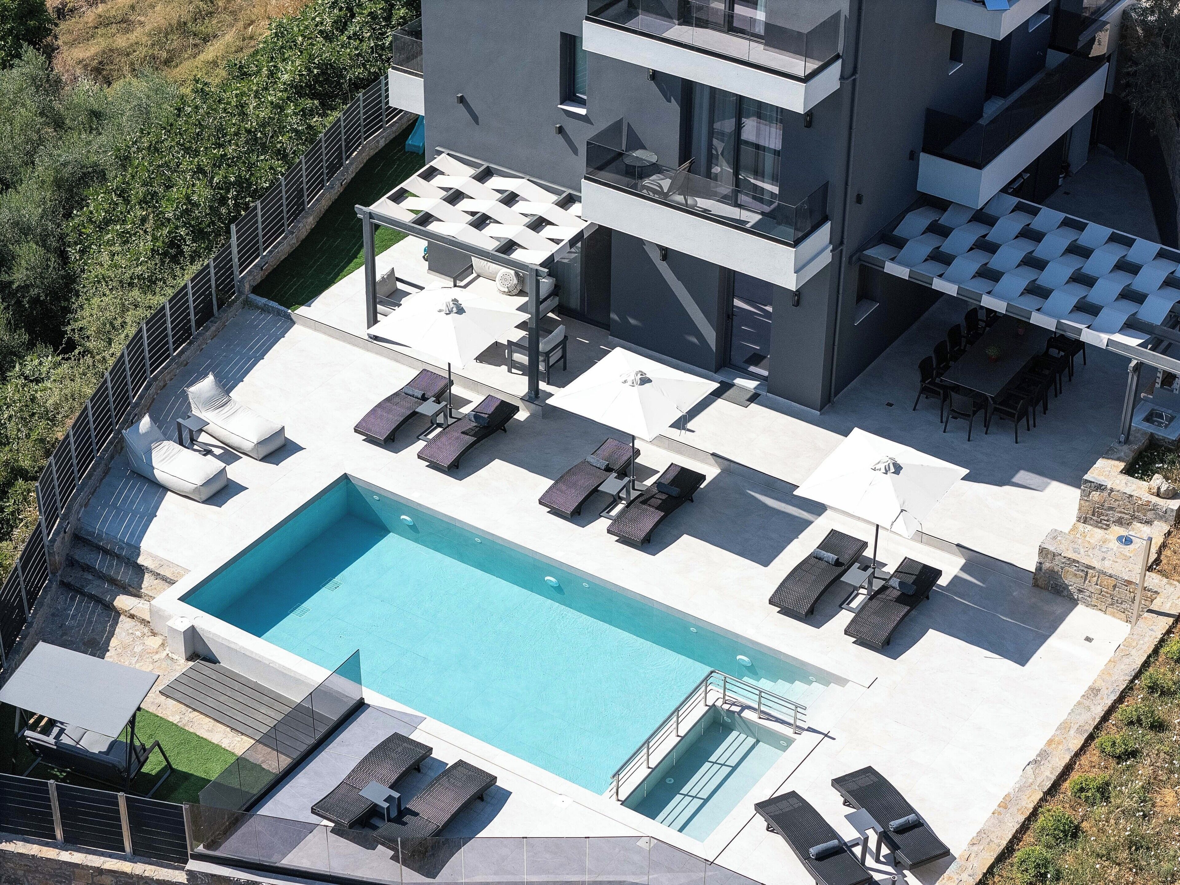 Ein modernes Gebäude mit Pool auf dem Dach, Außenbereich mit Sitzgelegenheiten und einer Glasbrüstung.