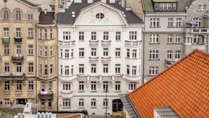 En byggnad med flera våningar, en central entré, stora fönster och balkonger.