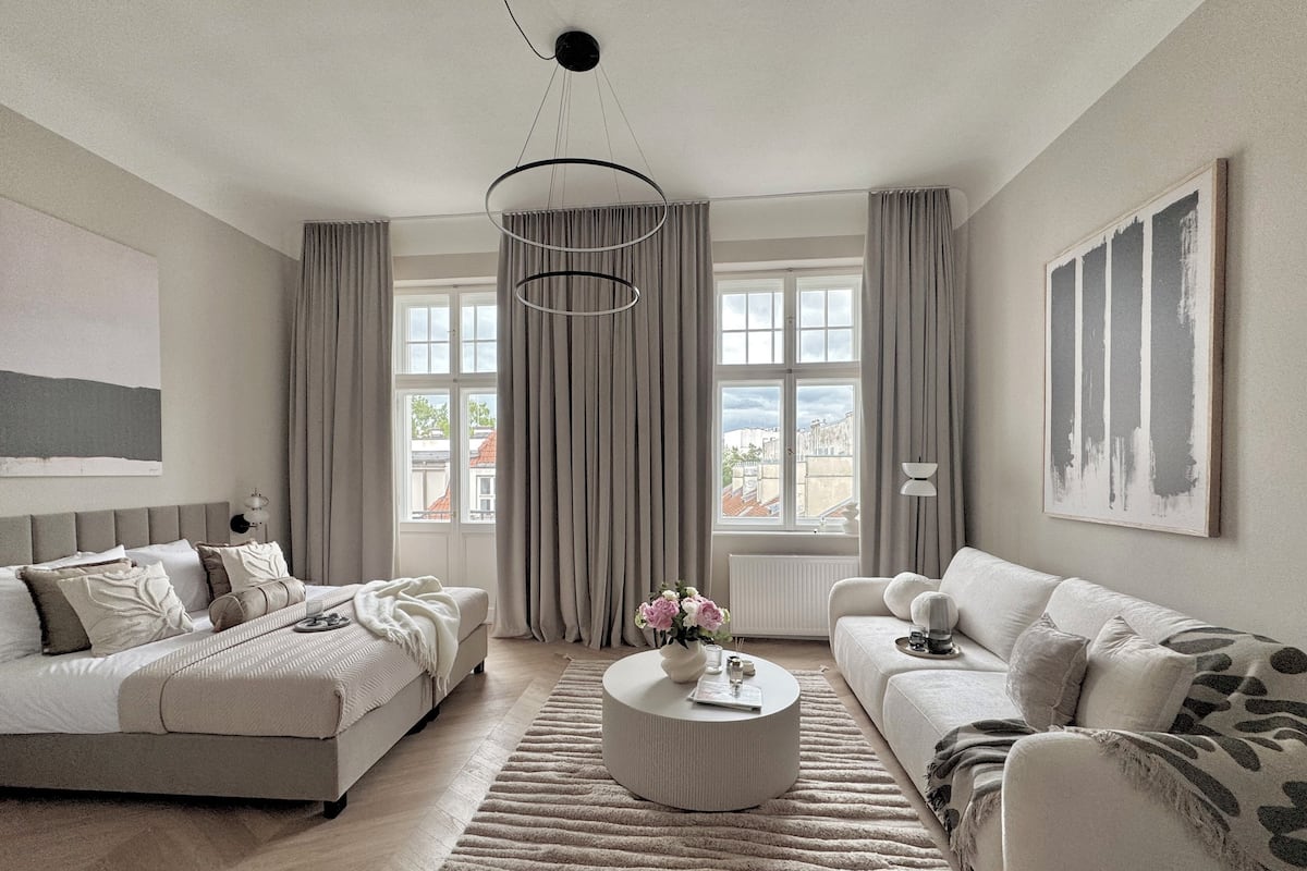 A modern living room with a sofa, a coffee table, and a view of the city through large windows.