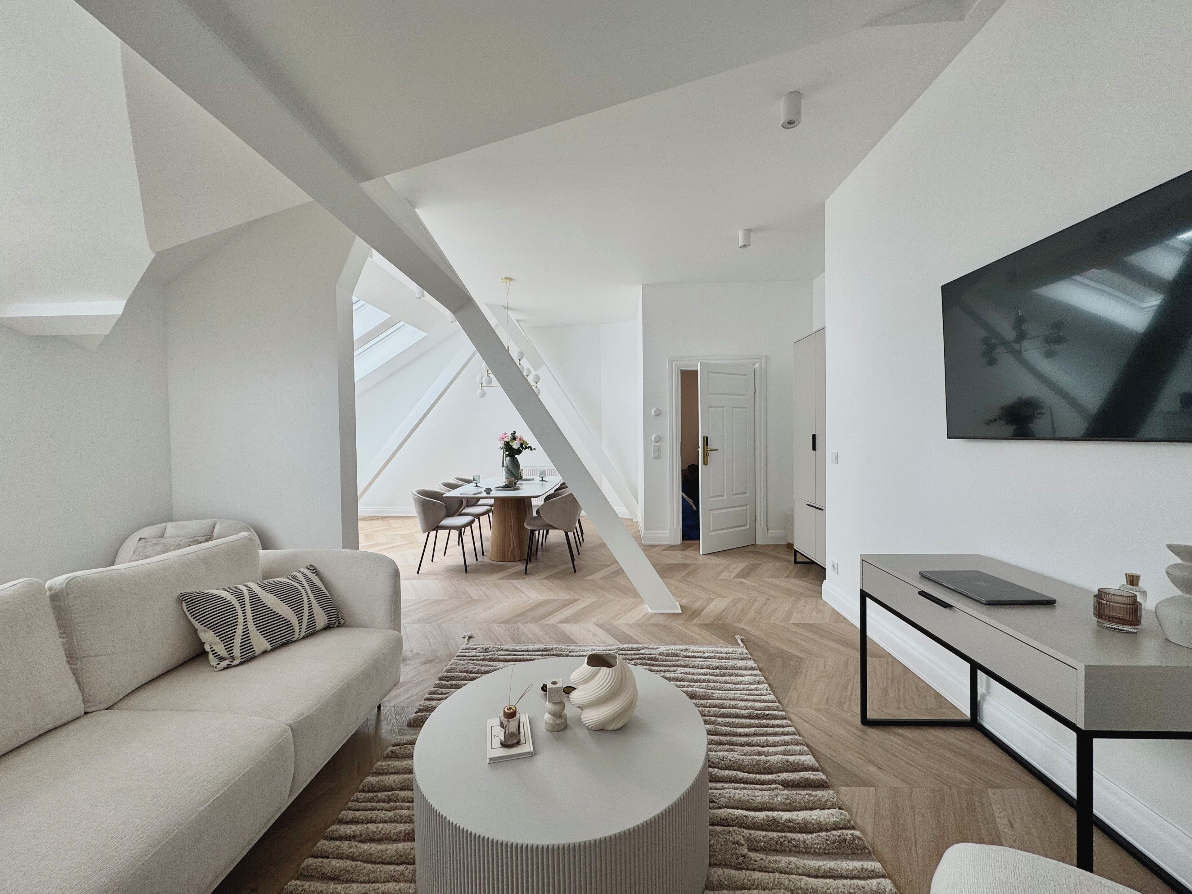 A modern living room with a sofa, coffee table, and a TV mounted on the wall.