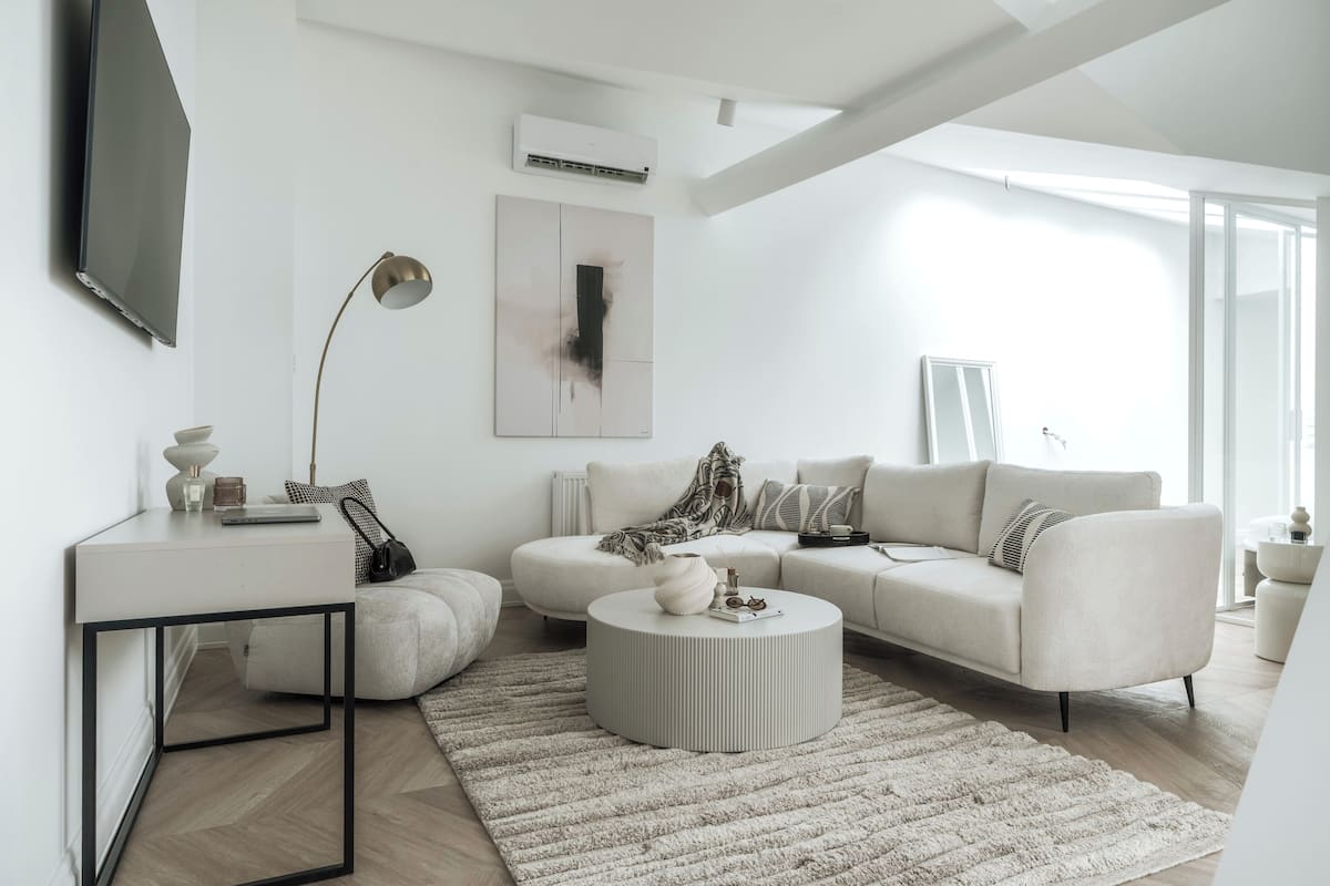 A modern living room with a sofa, coffee table, and a TV mounted on the wall.