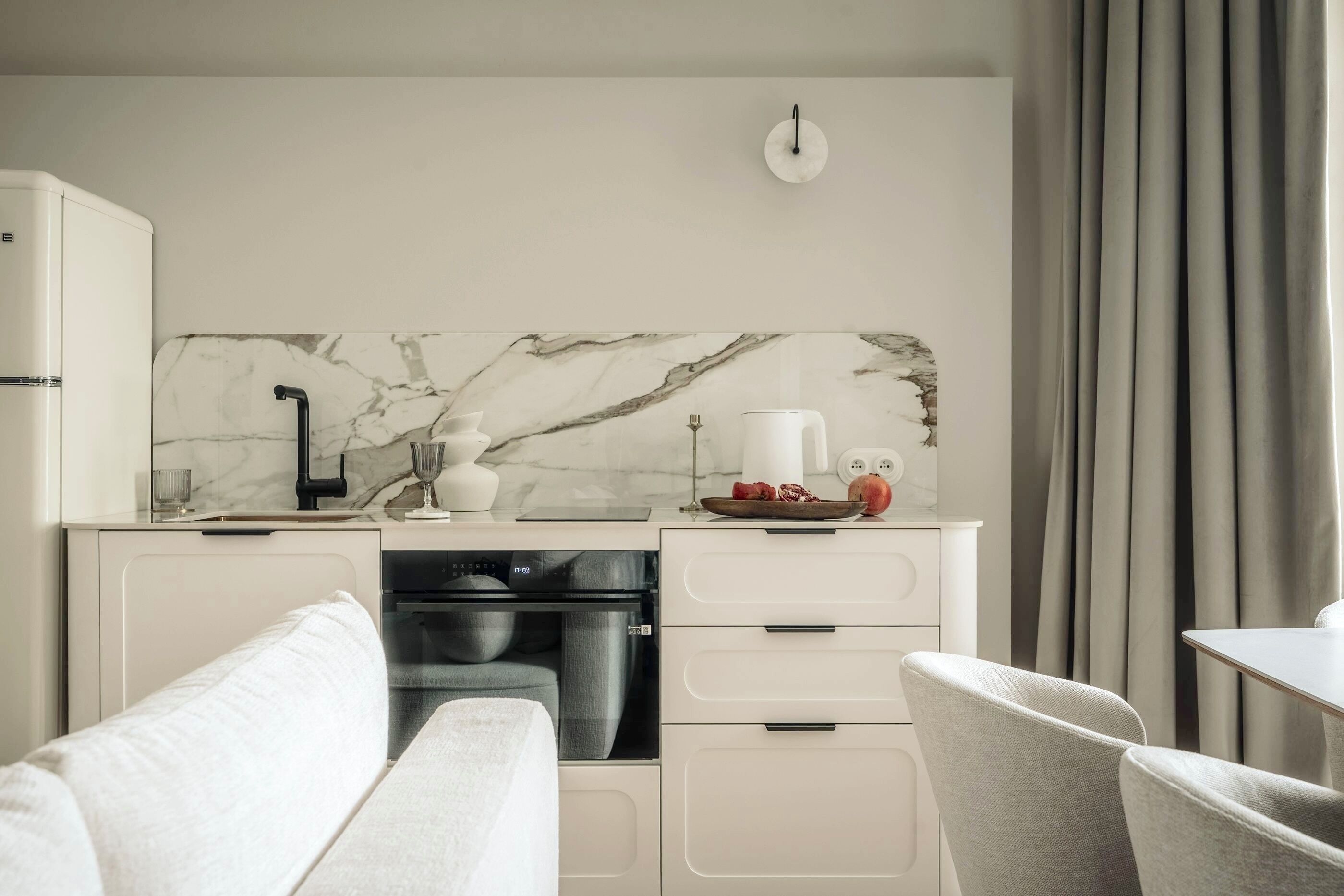Une cuisine moderne avec un dosseret en marbre, des meubles blancs et un coin repas comprenant une table et des chaises.