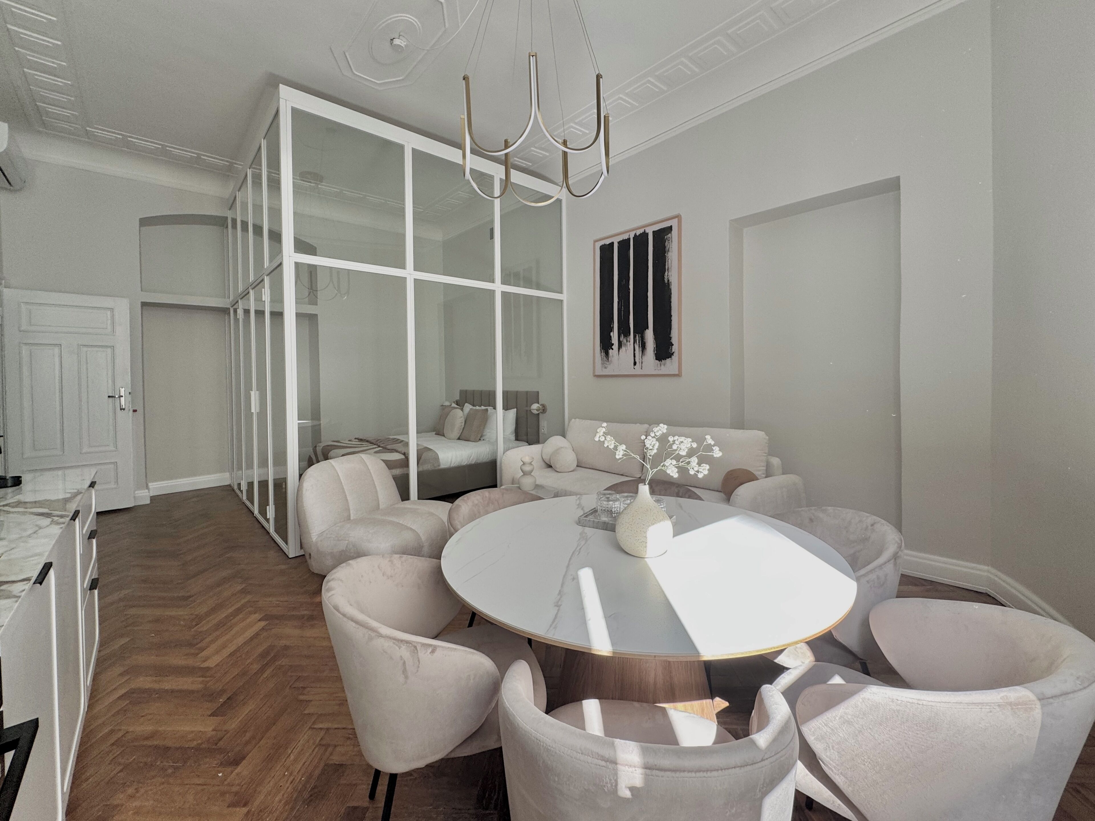 A modern dining area with a round table, cushioned chairs, and a chandelier.