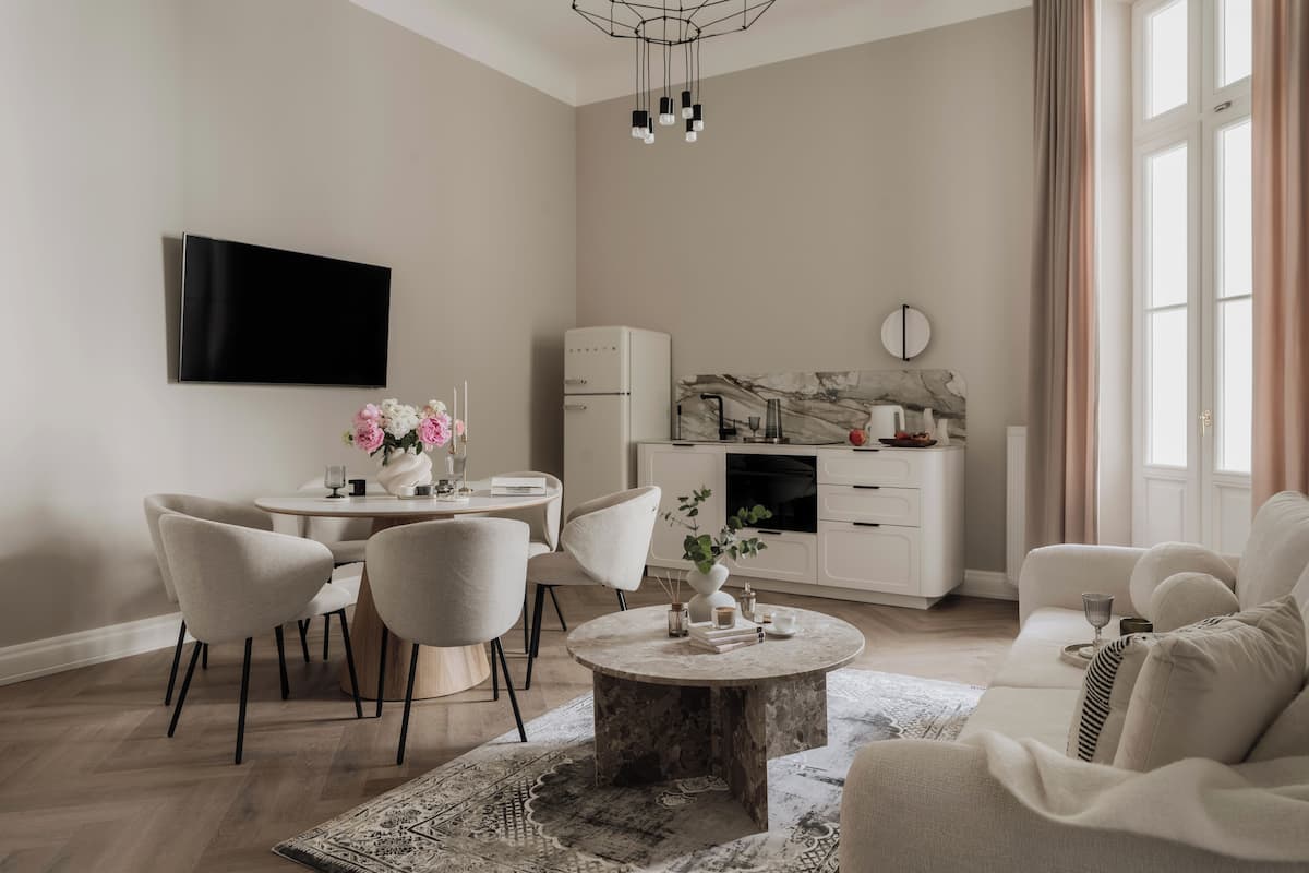 A modern living room with a round coffee table, a sofa, and a dining area with chairs and a small table.