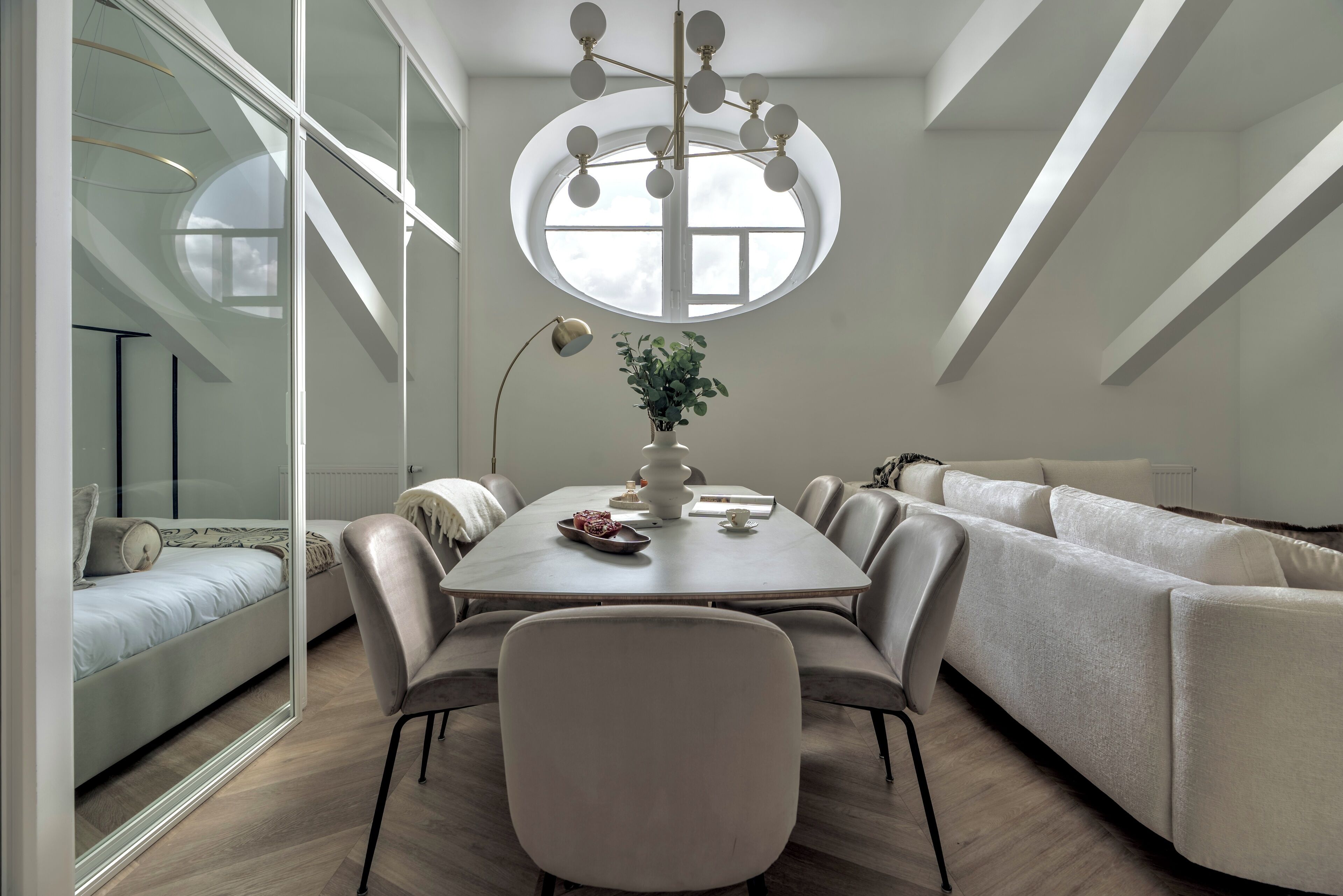Een moderne eethoek met een ronde tafel, stoelen en een groot raam.