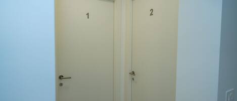 Dos puertas cerradas, con los números 1 y 2, en un pasillo de paredes blancas.