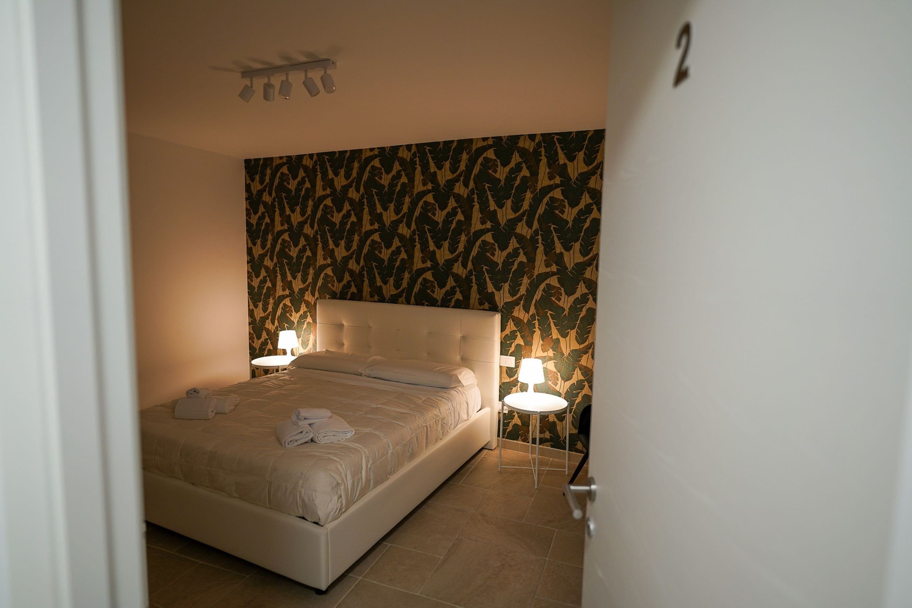 Una camera da letto con un letto grande, due abat-jour e carta da parati decorata.