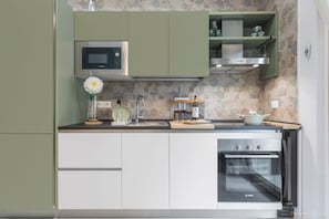 Een keuken met een Bosch magnetron, oven en spoelbak. Er staan kastjes, een bloevas en een wijnglas op het aanrecht.