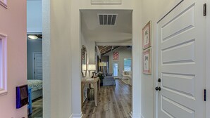 A hallway with a door, a lamp, a framed picture, and a sign on the wall.