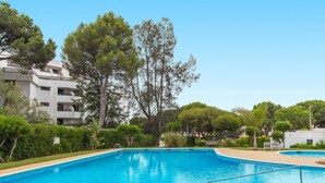 Una piscina con agua azul cristalina, rodeada de abundante vegetación y árboles.