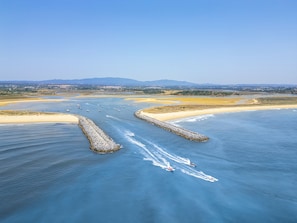 An aerial view of a coastal area with a clear sky, a sandy beach, and a waterway with boats. - Apartament Vilamoura Ruby (Loulé)