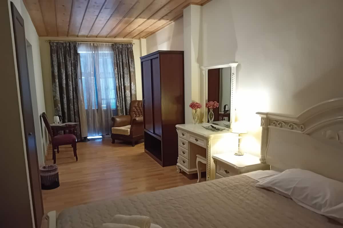 A bedroom with a bed, a dresser, a chair, a desk, and a wardrobe.