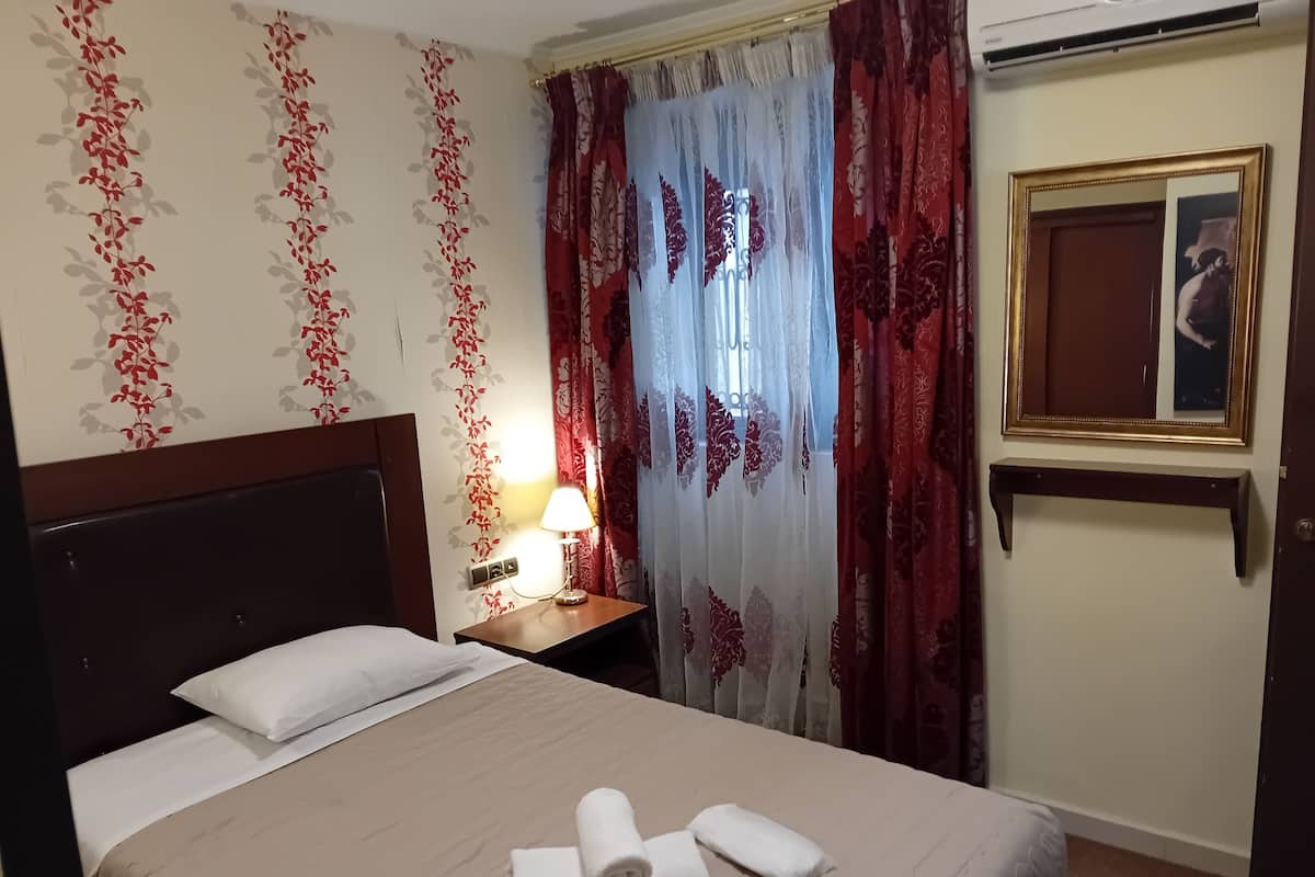 A hotel room with a bed, a nightstand, a lamp, and a mirror.