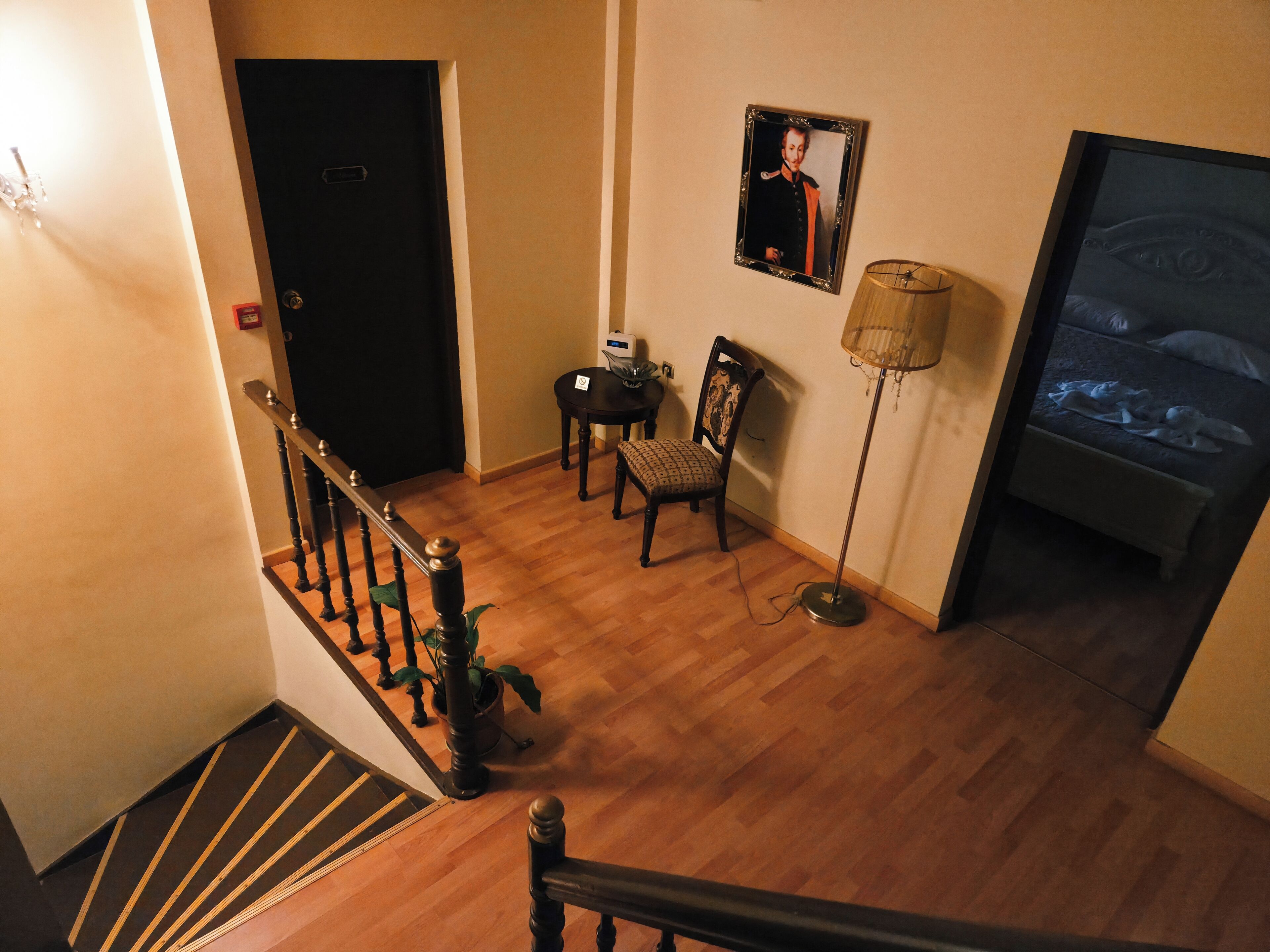 Eine Treppe mit Holzgeländer, ein Essbereich mit Tisch und Stühlen, eine Stehlampe und ein Bett mit Fernseher.