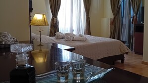 Une chambre d’hôtel avec un lit, une table avec des verres et une bouteille, une lampe et des rideaux.
