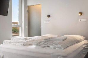 Een hotelkamer met een bed, twee wandlampen en een raam.