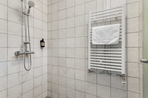 A bathroom with a shower, a towel rack, and a bottle of shampoo. - Swan Double Studio for 2 (Reykjavík)