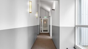 A corridor with a carpeted floor, white walls, and a door at the end.