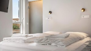 A hotel room with a bed, two wall-mounted light fixtures, and a window.