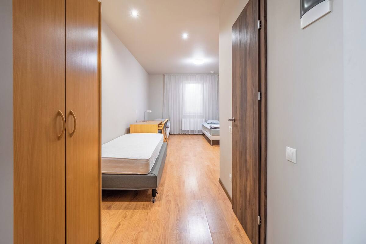 Une chambre d’hôtel avec une armoire en bois, un lit, un bureau et une fenêtre avec des rideaux.