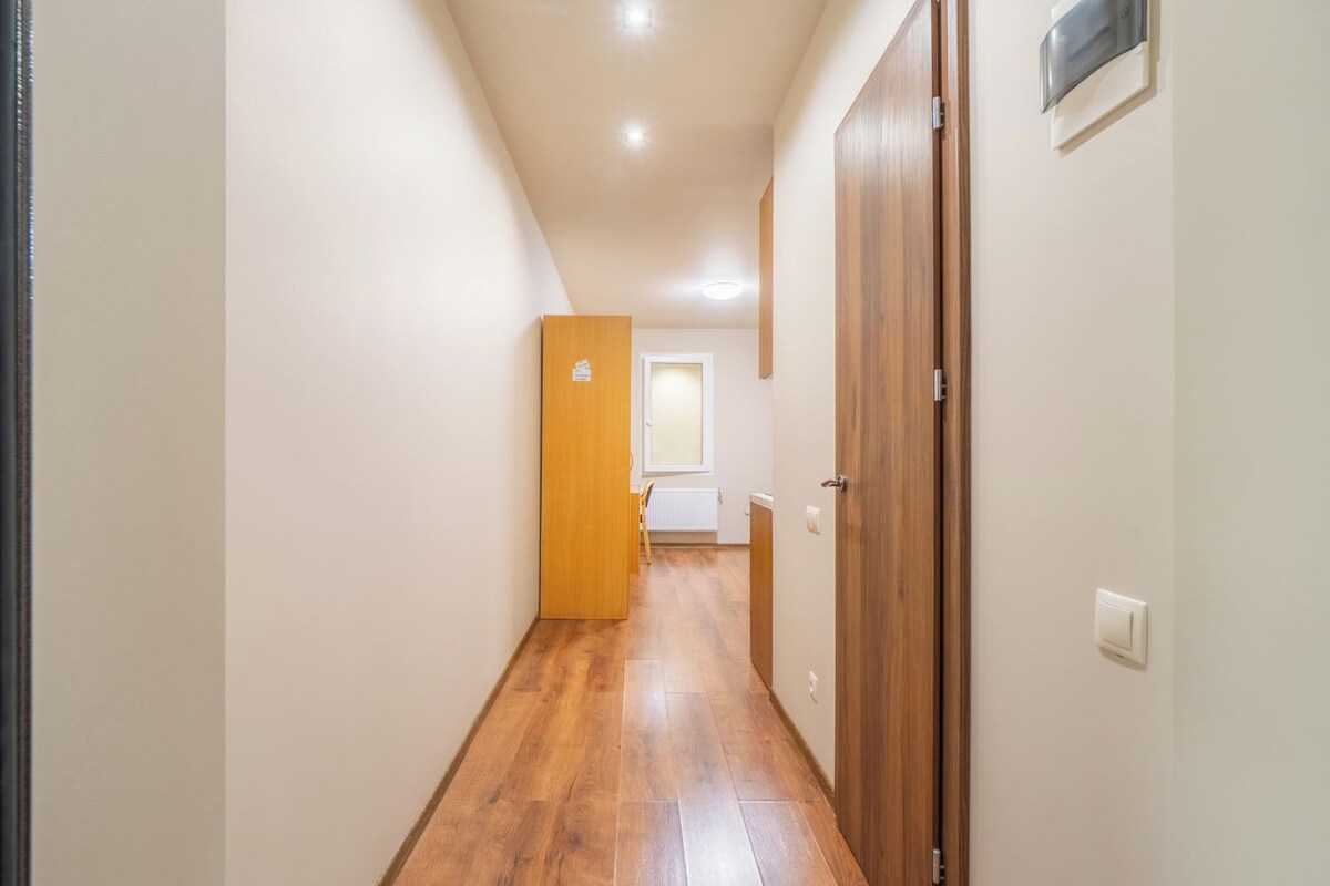 A narrow hallway with wooden flooring and white walls.