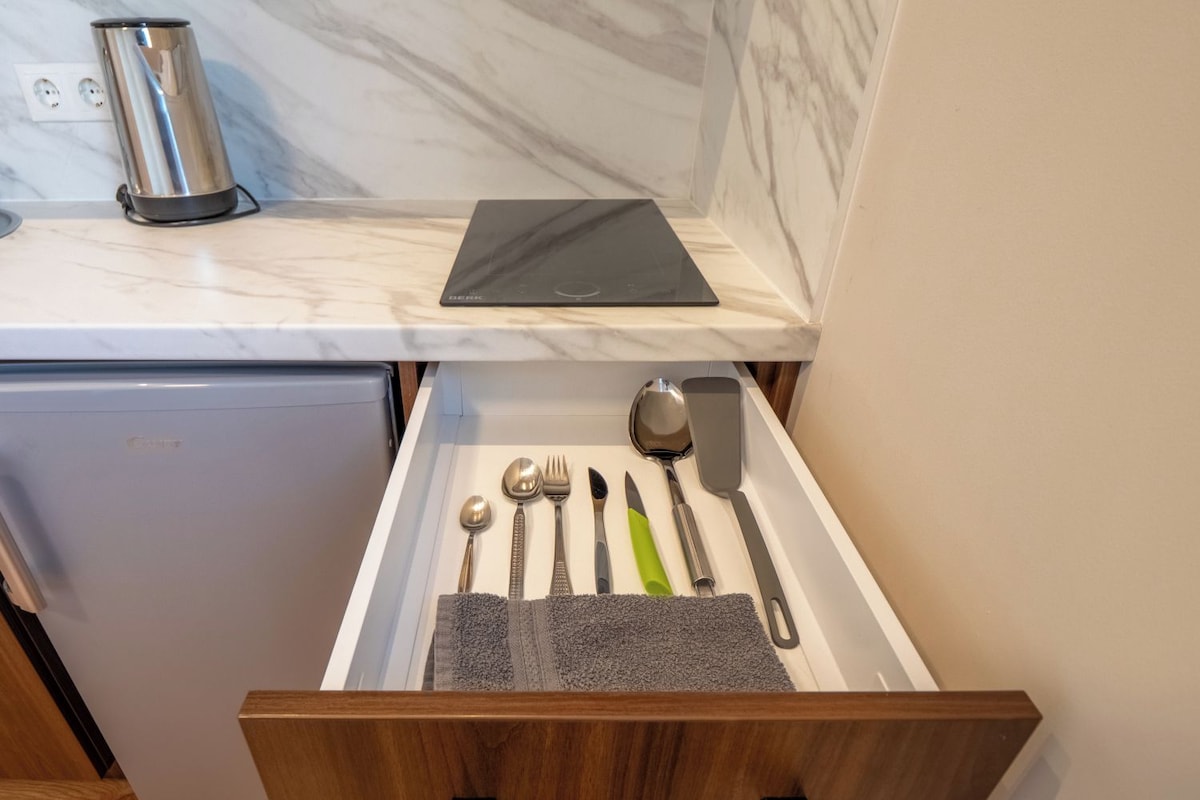 A kitchen drawer with utensils, a tablet, and a kettle.