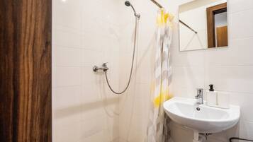 A bathroom with a shower, a sink, and a mirror.