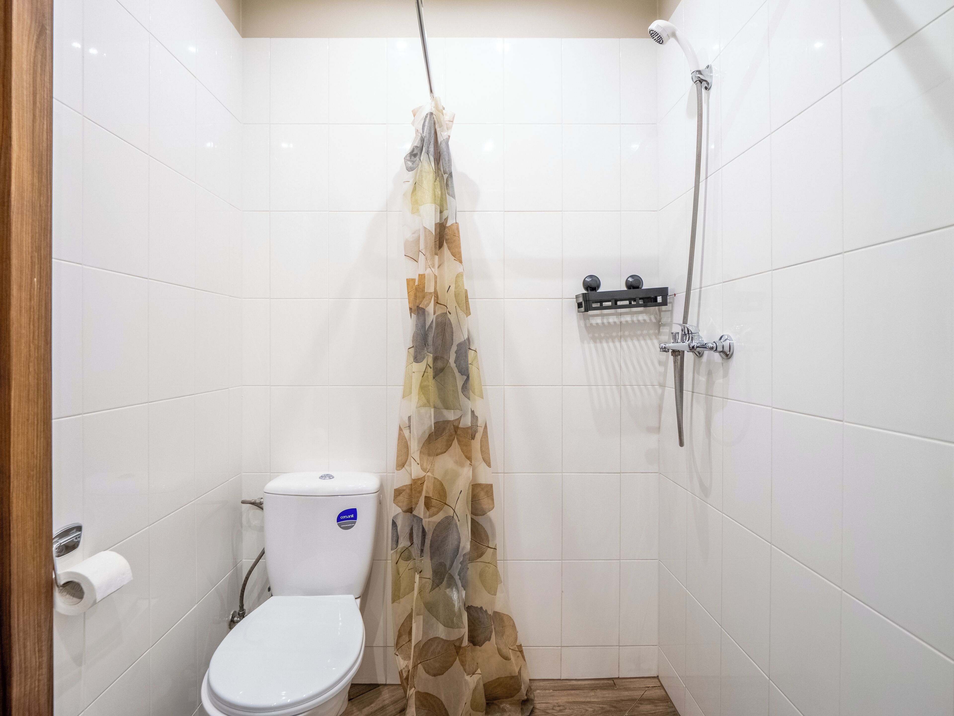 Pieni kylpyhuone, jossa on wc, suihku ja wc-paperiteline.