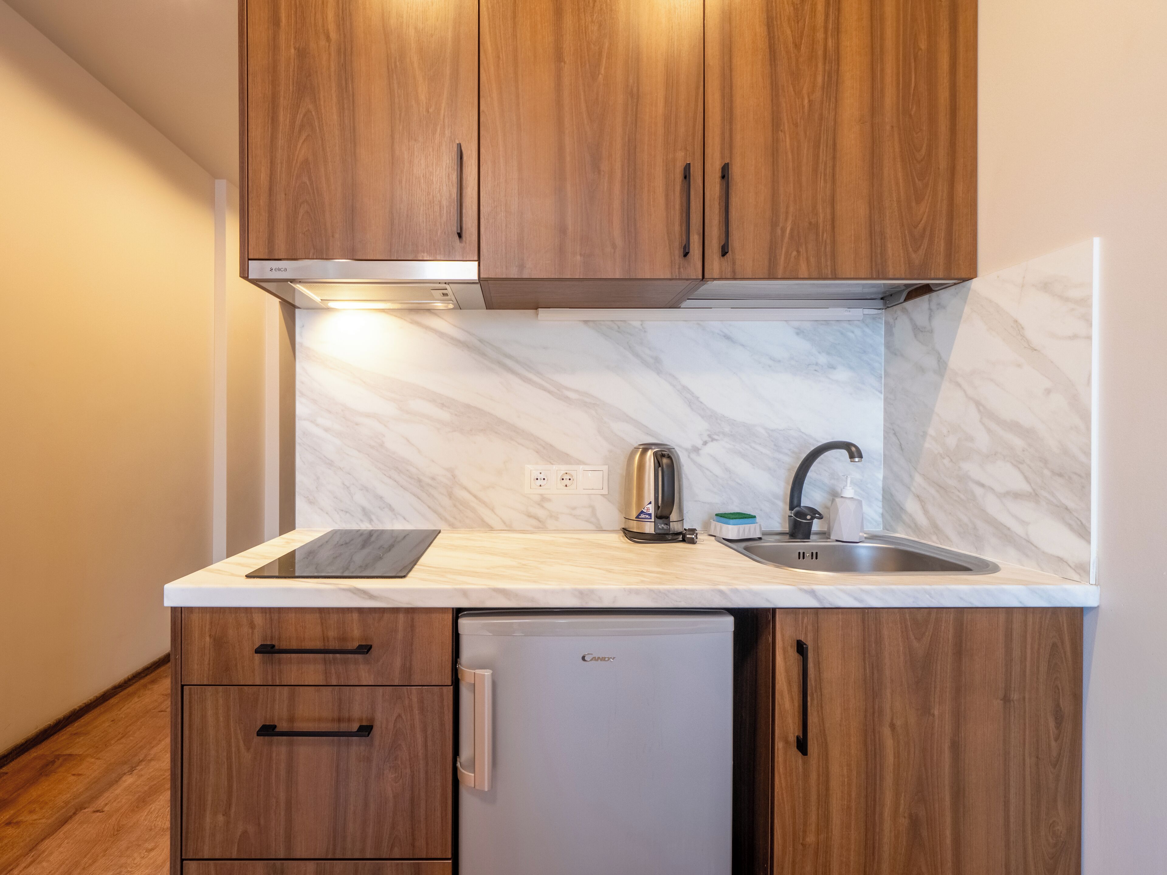 A compact kitchen with wooden cabinets, a built-in sink, and a refrigerator.