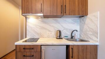 A compact kitchen with wooden cabinets, a built-in sink, and a refrigerator.