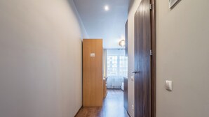 Ein Korridor mit Holzboden, einer Holztür und einem Lichtschalter an der Wand.