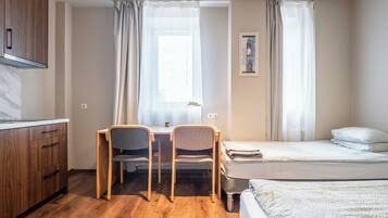 Une chambre à coucher de taille réduite, comprenant un lit, un bureau et des chaises.