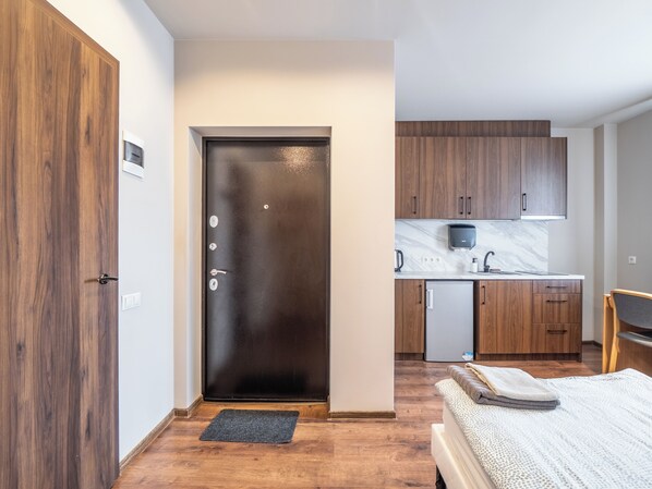 A modern kitchen with wooden cabinets, a marble countertop, and a built-in microwave. - RVR Smart Apartment with Self-check-in (Riga)