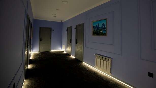A hallway with a carpeted floor, white walls, and doors. - Will Hotel (Baku)
