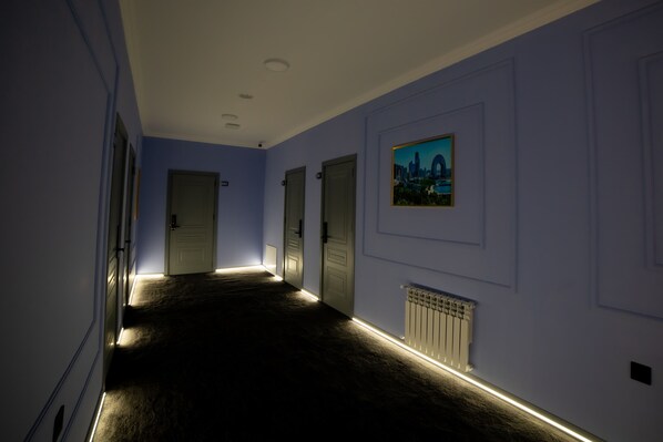 A hallway with a carpeted floor, white walls, and doors. - Will Hotel (Baku)