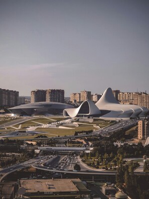 A modern architectural complex with unique curved structures, surrounded by high-rise residential buildings and a busy highway. - Will Hotel (Baku)