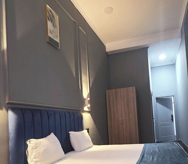 A hotel room with a bed, a wardrobe, and a door. - Will Hotel (Baku)