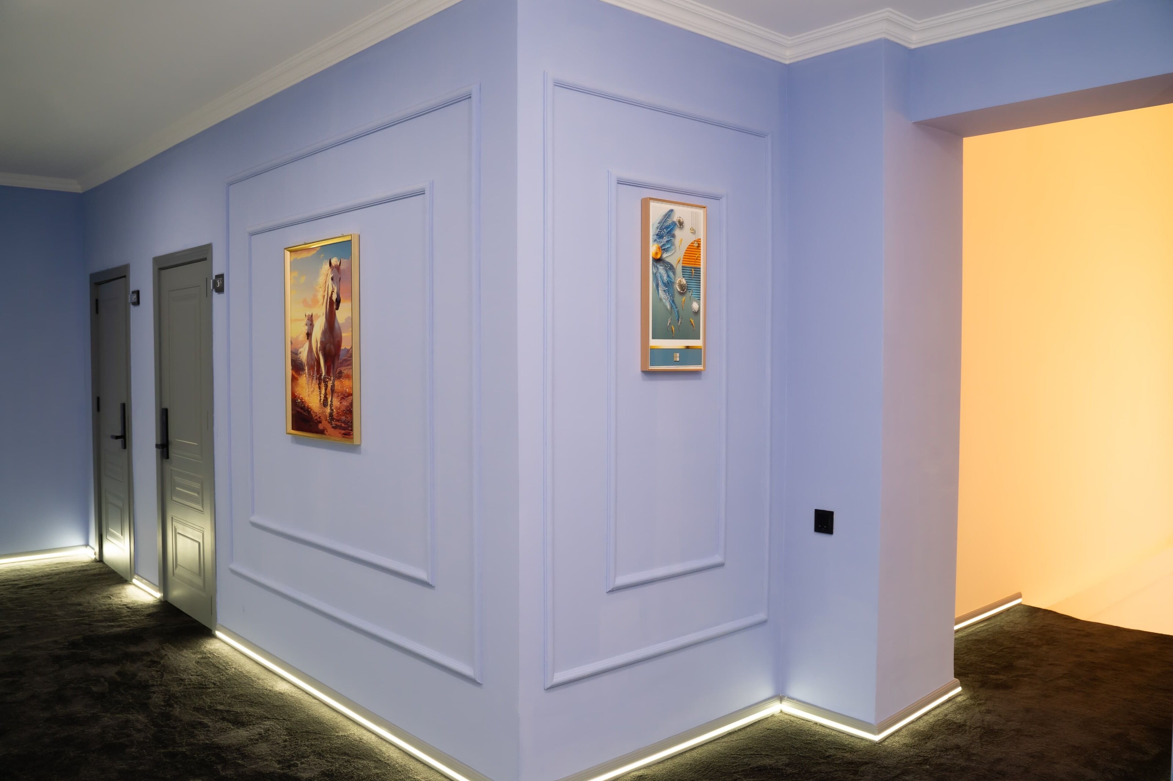 A hallway with light purple walls, two doors, and framed artwork on the walls.