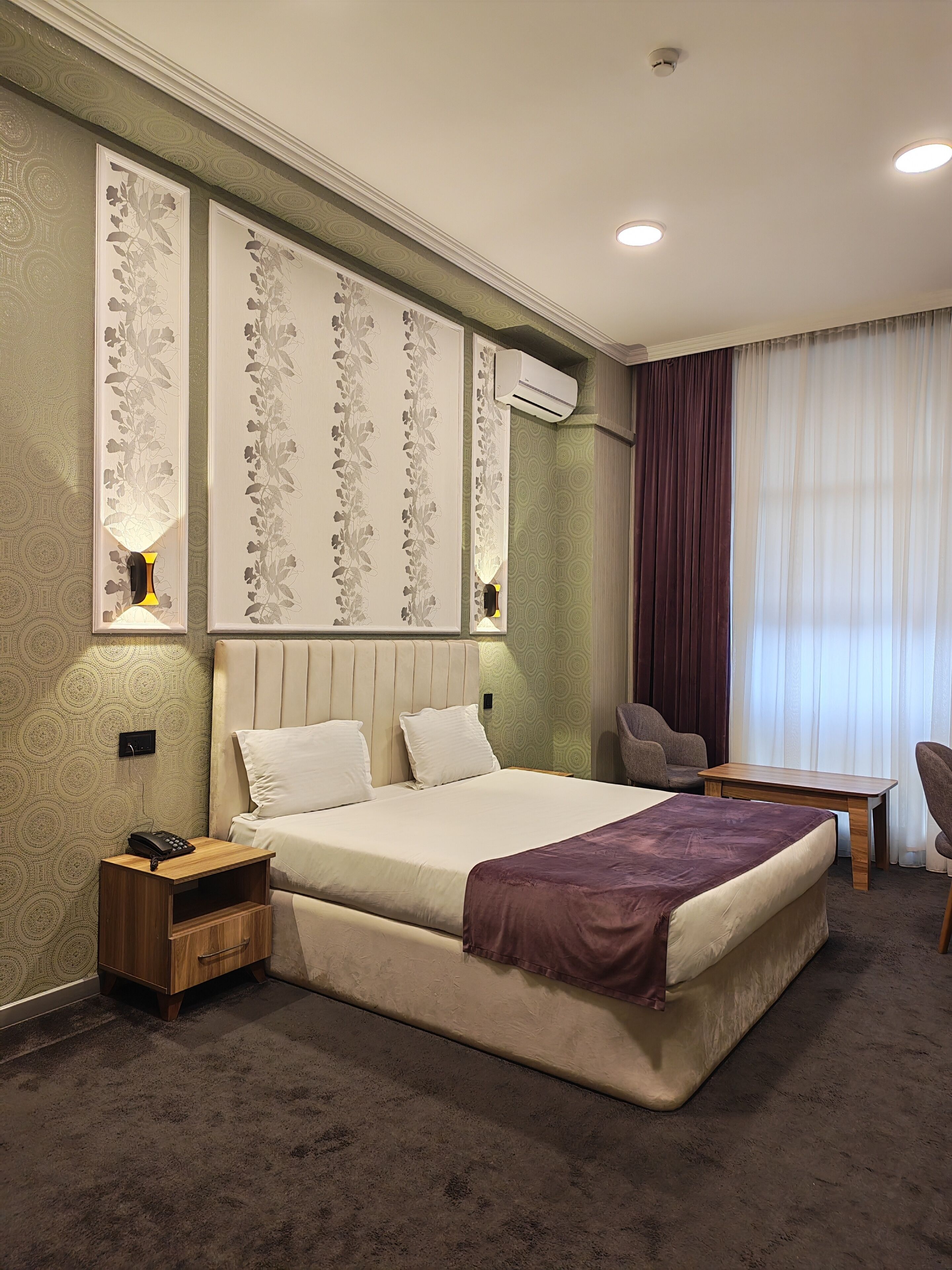 A hotel room with a large bed, bedside tables, a desk, and a chair.