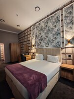 Una habitación de hotel con una cama grande, un escritorio, un armario y paneles decorativos en la pared.