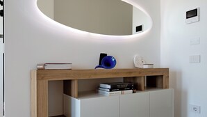 A modern vanity with a wooden frame, a built-in mirror, and a shelf with books and a blue mug.