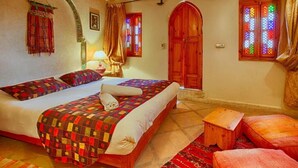 A cozy bedroom with a large bed, a wooden wardrobe, and a small wooden stool. - RIAD KENZO (Marrakech)