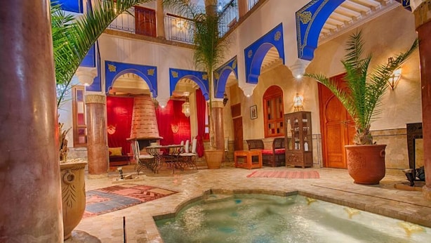 A luxurious indoor pool area with a fountain, surrounded by arches and traditional decor. - RIAD KENZO (Marrakech)