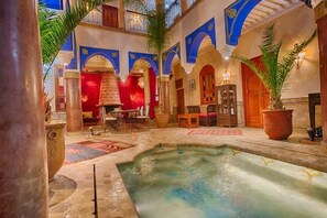 A luxurious indoor pool area with a fountain, surrounded by arches and traditional decor. - RIAD KENZO (Marrakech)
