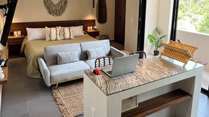 Una camera da letto moderna con un letto, un divano, una scrivania con un portatile e una ventola a soffitto.