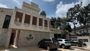 Un edificio con facciata in pietra, un cartello con la scritta 'nayal' e un'area di parcheggio con diverse auto.