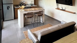 Una cucina moderna con isola integrata, sgabelli da bar, frigorifero e televisore a schermo piatto montato a parete.