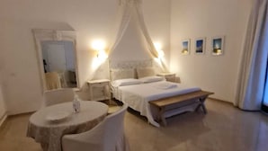 Un dormitorio con una cama, una mesita de noche, una silla, una pequeña mesa y un espejo.