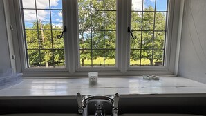 A bathroom with a window, a sink, and a candle on the windowsill.