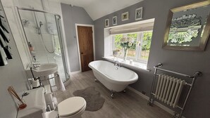 A bathroom with a freestanding bathtub, a shower, a sink, and a toilet.